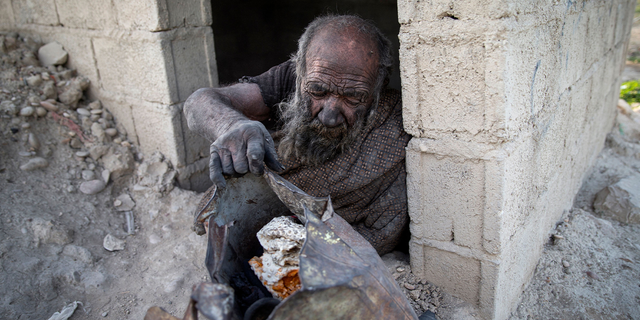 Amou Haji sits in front of an open brick shack that villagers constructed for him on the outskirts of Dezhgah, Iran, on Dec. 28, 2018.