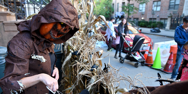 Designer Barb Salzman, of Hatch Creative Studio, hands out candy to children in treat or treat on October 31, 2021 in New York City.  Earlier this month, Dr. Anthony Fauci announced "to go out and enjoy Halloween" citing trick or treating and other activities held outdoors pose little risk to those vaccinated.