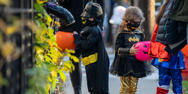 Children get treats from candy chutes while trick-or-treating for Halloween in Woodlawn Heights on October 31, 2020 in New York City.  The CDC shared on its website alternative ways to still celebrate the holiday while being safe.
