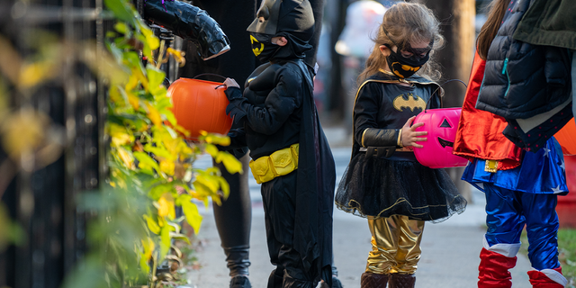 Children get treats from candy chutes while trick-or-treating for Halloween in Woodlawn Heights on October 31, 2020 in New York City. The CDC shared on its website alternative ways to still celebrate the holiday while being safe.