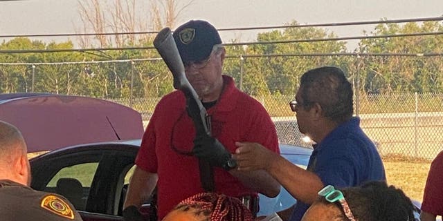 A police officer looks over a gun turned in during a buyback event in Houston, Texas on Oct. 8, 2022.