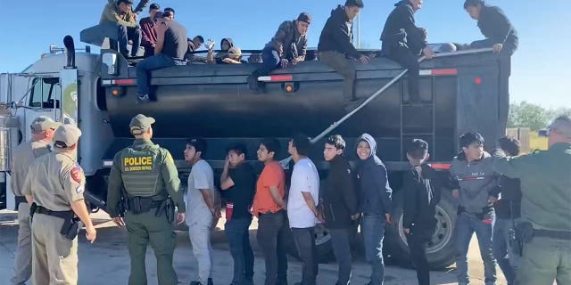 Officers walk around line of immigrants