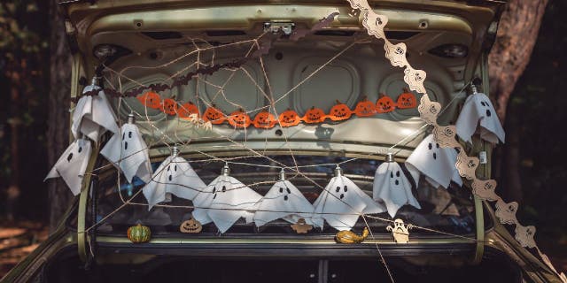 Distribuidores de balas ou travessuras decoram os porta-malas de seus carros para doces ou travessuras de Halloween.