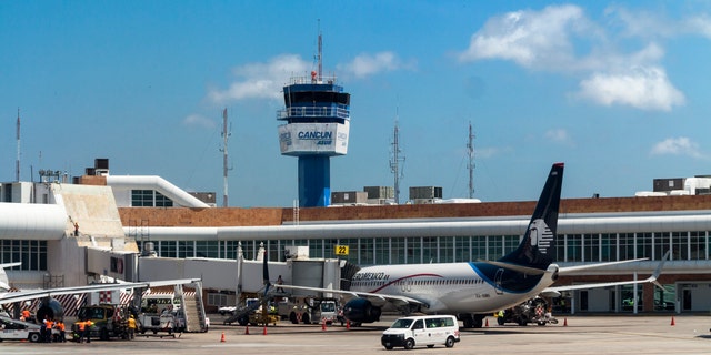 Cancun, Mexico - April 24, 2015: The control tower of the international airport of Cancun with an Aero Mexico airplane.