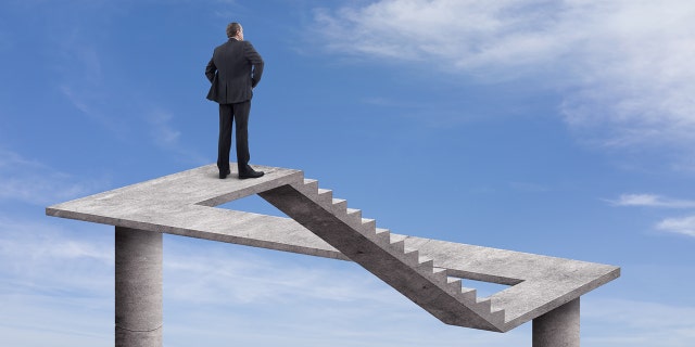 Rearview of businessman standing on a floating staircase with cloudy sky background. This digitally generated image points to the metaphysical.