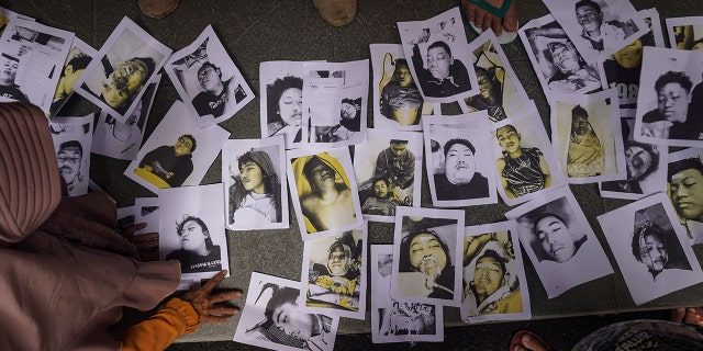 People looking for their relatives inspect photographs of soccer riot victims provided by volunteers to help them identify their family members in Malang, East Java, Indonesia, Sunday, Oct. 2, 2022.