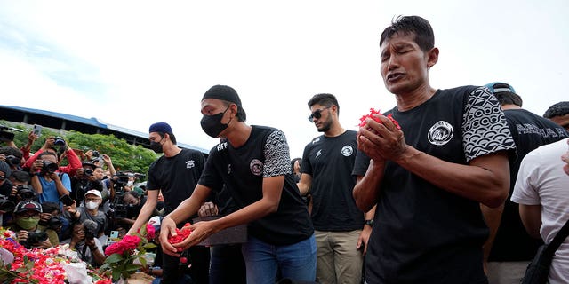 Players and officials of the soccer club Arema FC pray outside the Kanjuruhan Stadium where many fans lost their lives in a stampede Saturday night in Malang, Indonesia, Monday, Oct. 3, 2022. Police firing tear gas at Saturday night's match between host Arema FC of East Java's Malang city and Persebaya Surabaya in an attempt to stop violence triggered a disastrous crush of fans making a panicked, chaotic run for the exits, leaving a large number of people dead, most of them trampled upon or suffocated. 