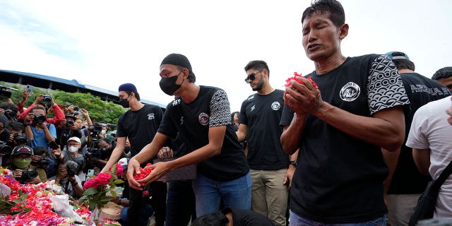 Players and officials of the soccer club Arema FC pray outside the Kanjuruhan Stadium on Monday, where many fans lost their lives in a stampede Saturday night in Malang, Indonesia.