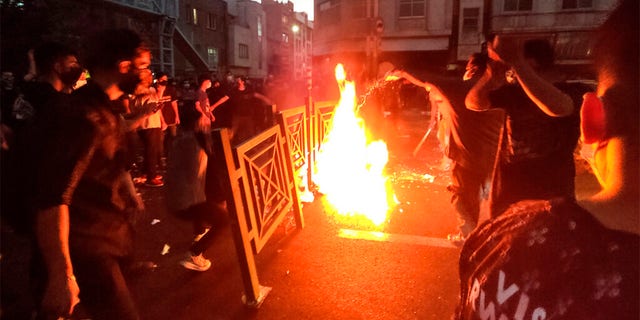 En ce mercredi 21 septembre 2022, photo prise par un individu non employé par l'Associated Press et obtenue par l'AP hors d'Iran, des manifestants font feu et bloquent la rue lors d'une manifestation contre la mort d'une femme détenue par le police des mœurs, au centre-ville de Téhéran, en Iran. 