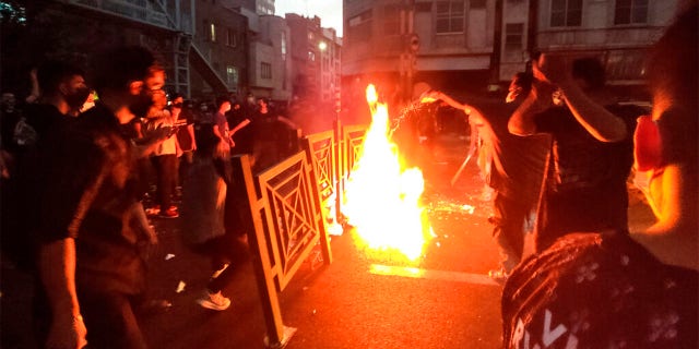 En ce mercredi 21 septembre 2022, photo prise par un individu non employé par l'Associated Press et obtenue par l'AP hors d'Iran, des manifestants font feu et bloquent la rue lors d'une manifestation contre la mort d'une femme détenue par le police des mœurs, au centre-ville de Téhéran, en Iran. 