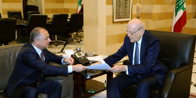 In this photo released by Lebanon's official government photographer Dalati Nohra, Lebanese Prime Minister Najib Makati, right, receives the final draft of the maritime border agreement between Lebanon and Israel from his deputy Elias Bou Saab who leads the Lebanese negotiating team, in Beirut, Lebanon, Tuesday, Oct. 11, 2022.