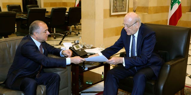 In this photo released by Lebanon's official government photographer Dalati Nohra, Lebanese Prime Minister Najib Makati, right, receives the final draft of the maritime border agreement between Lebanon and Israel from his deputy Elias Bou Saab who leads the Lebanese negotiating team, in Beirut, Lebanon, Tuesday, Oct. 11, 2022.