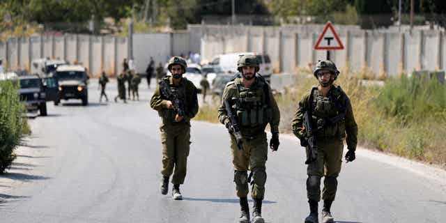 Israeli soldiers work near the site where an Israeli soldier was shot dead by Palestinian militants near the Jewish settlement of Shavei Shomron in the West Bank on 11 October 2022.