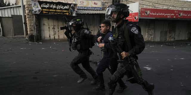 Israeli police are seen here arresting a Palestinian man during clashes in the Shuafat refugee camp in Jerusalem, on Oct.12. 2022.