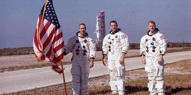 Apollo 9 astronauts James A. McDivitt (left), David R. Scott (middle) and Russell L. Schweickart (right) pose for a photo with the American flag in this undated photo.