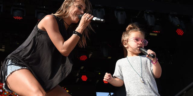 Jana Kramer performing on stage with her daughter Jolie. 