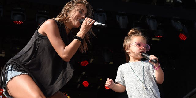 Jana Kramer performing on stage with her daughter Jolie. 