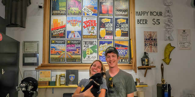 Judy and Rob Neff hold their dog, Dixie, at Checkerspot Brewery in Baltimore, Maryland.