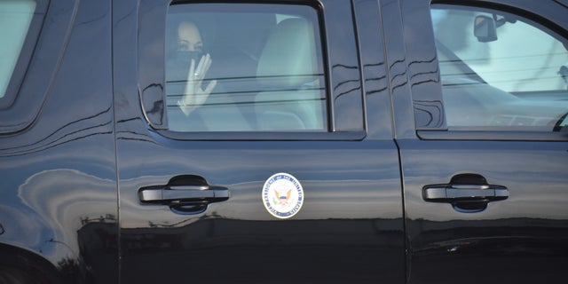 Vice President Kamala Harris waves from the window of her motorcade vehicle.