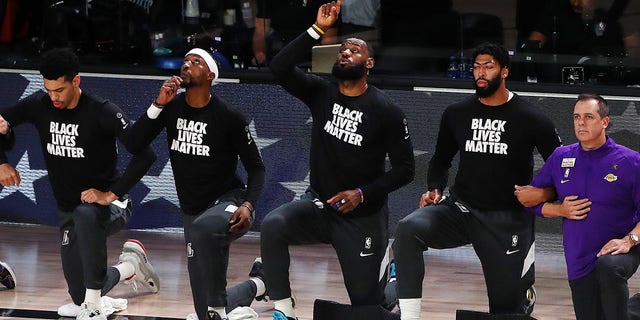 LeBron James, Anthony Davis and Frank Vogel of the Los Angeles Lakers kneel during the national anthem prior to a game against the Houston Rockets in Game 5 of the 2020 Western Conference playoffs Sept. 12, 2020, in Lake Buena Vista, Fla.