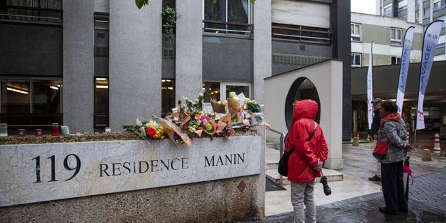 Members of the public stand in front of bunches of flowers displayed outside the building in Paris  where Lola lived with her family on October 17.