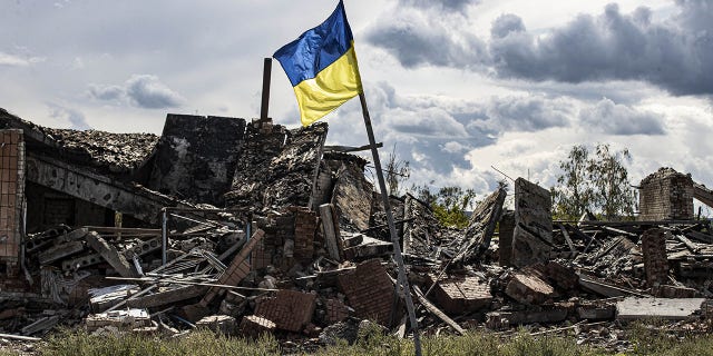 Uma bandeira ucraniana tremula em uma área residencial fortemente danificada na vila de Dolyna em Donetsk Oblast, Ucrânia, após a retirada das tropas russas em 24 de setembro.