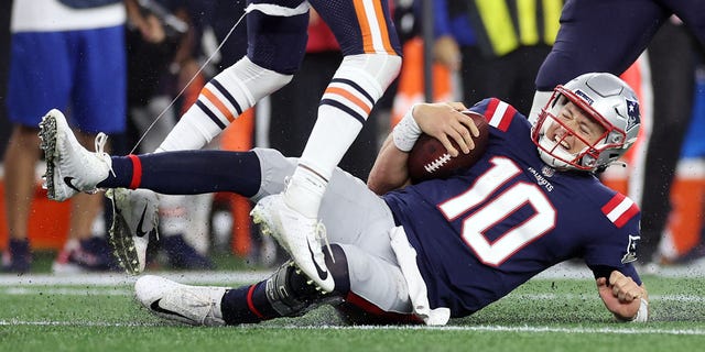 #10 Mac Jones of the New England Patriots slides after a first-half run with the ball against the Chicago Bears at Gillette Stadium on October 24, 2022 in Foxborough, Massachusetts.