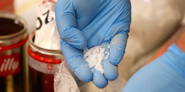 A customs officer shows crystal meth hidden in coffee cans at Cologne Bonn Airport, Sept. 27, 2022.