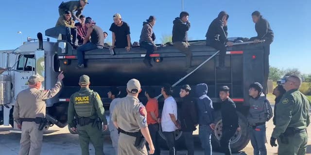 Migrants climb out of a dump truck.