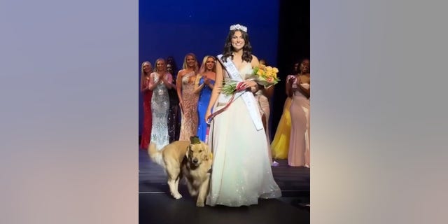 La nueva reina de belleza adolescente de Dallas, Allison Appleby, sube al escenario después de su victoria con su perro de servicio, Brady, a su lado.