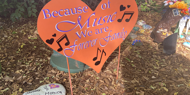 A sign at the Las Vegas Healing Garden reads "Because of Music we are forever family."