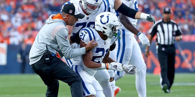 Nyheim Hines #21 of the Indianapolis Colts was helped to his feet by #79 after being hit during a game against the Denver Broncos on Oct. 6, 2022 at Empower Field at Mile High in Denver, Colorado.