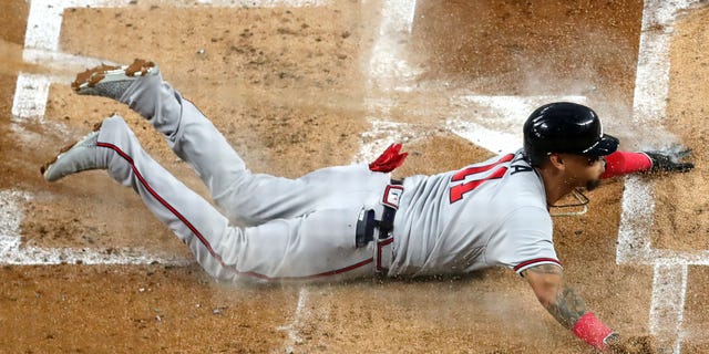 Orlando Arcia, #11 of the Atlanta Braves, slides home against the Miami Marlins during the second inning of the game at loanDepot park on Oct. 4, 2022 in Miami.