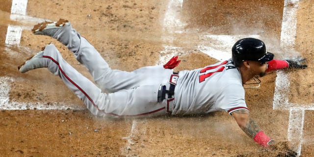 Orlando Arcia, #11 of the Atlanta Braves, slides home against the Miami Marlins during the second inning of the game at loanDepot park on Oct. 4, 2022 in Miami.