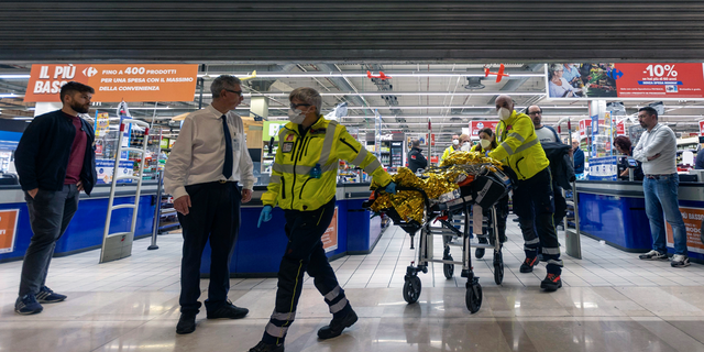 Emergency personnel wheel an injured person at the scene of an attack in Milan, Italy, Thursday Oct. 27, 2022.