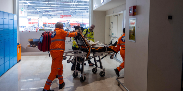 Emergency personnel wheel an injured person at the scene of an attack in Milan, Italy, Thursday Oct. 27, 2022.
