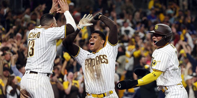 Juan Soto #22 and Ha-Seong Kim #7 celebrate with Manny Machado #13 of the San Diego Padres after scoring two runs during the seventh inning to go up 5-3 against the Los Angeles Dodgers in game four of the National League Division Series at PETCO Park on October 15, 2022 in San Diego, California.
