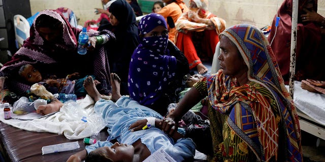 Women sit with their children suffering from malaria, as they receive medical assistance at Sayed Abdullah Shah Institute of Medical Sciences in Sehwan, Pakistan, on Sept. 29, 2022. 