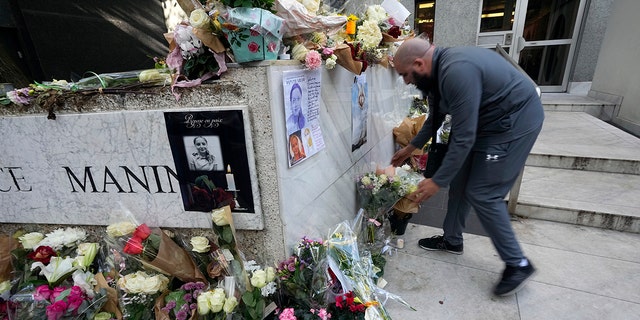 A man lays flowers outside the building where the body of 12-year-old schoolgirl was discovered in a trunk, in Paris, Wednesday, Oct. 19, 2022.