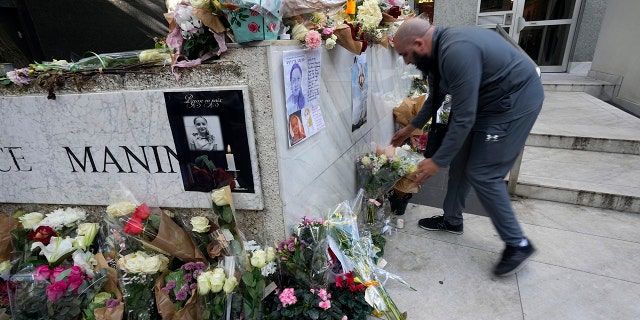 A man lays flowers outside the building where the body of 12-year-old schoolgirl was discovered in a trunk, in Paris, Wednesday, Oct. 19, 2022.