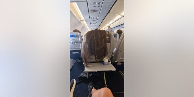 A plane passenger captures a fellow traveler draping her long hair over the back of her seat amid a flight from Athens to Amsterdam on Sept. 29, 2022.