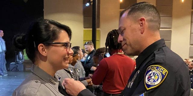 Escondido police Sgt. Jeff Valdivia pins the badge on the uniform of El Paso County Deputy Natalie Young following her graduation ceremony.
