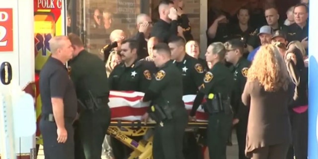 Deputies salute the flag-draped body of a Polk County Deputy Sheriff Blane Lane, 21, as they place him into an ambulance on Tuesday morning.