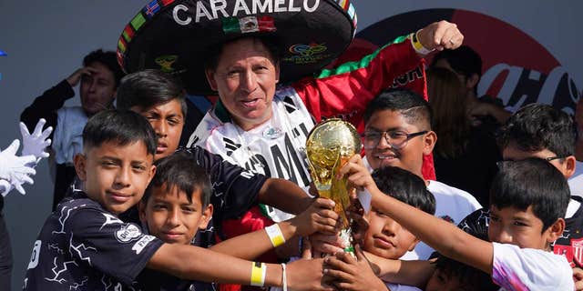 Mexican National team fans pose with a replica World Cup trophy in Mexico City, on Oct. 16, 2022.