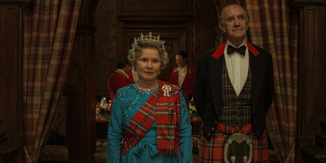 Imelda Stauton, Queen Elizabeth II, is seen standing tall in what appears to be Scotland, next to her husband, Prince Philip, played by Jonathan Pryce. 