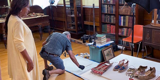 Leola One Feather (left) of the Oglala Sioux Tribe in South Dakota looks over Sioux artifacts at the Founders Museum in Barre, Massachusetts, on July 19, 2022.