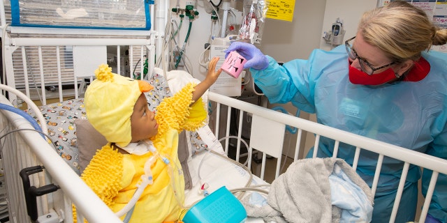 A child in the hospital dressed in a costume interacts with a nurse during a Halloween party thrown by Spirit of Children.
