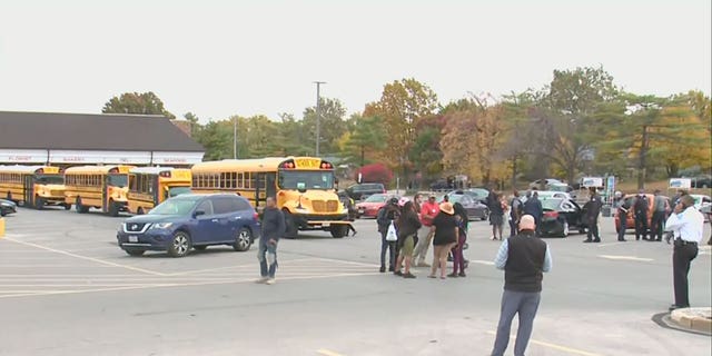 Students, teachers and parents stand in the parking lot outside Central Visual and Performing Arts high school in St. Louis after an active shooting incident. (KMOV)