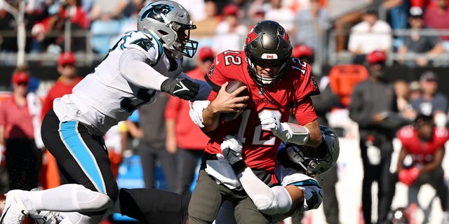 Frankie Love (left) of the Carolina Panthers tackles Tom Brady of the Tampa Bay Buccaneers in the third quarter at Bank of America Stadium in Charlotte, NC on October 23, 2022