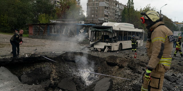 Firefighters and police officers work at the site where an explosion created a crater in the street after a Russian attack in Dnipro, Ukraine, Monday, October 10, 2022.  (AP Photo/Leo Correa)